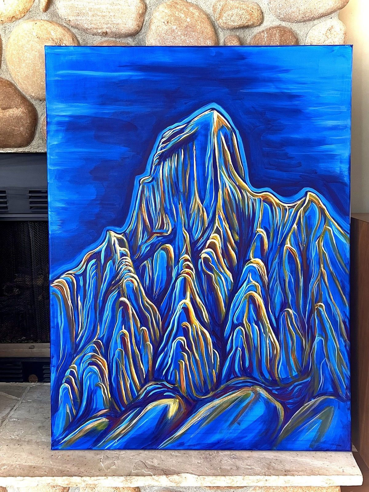 Blue and gold acrylic painting of a peak above a wall of fluted spines