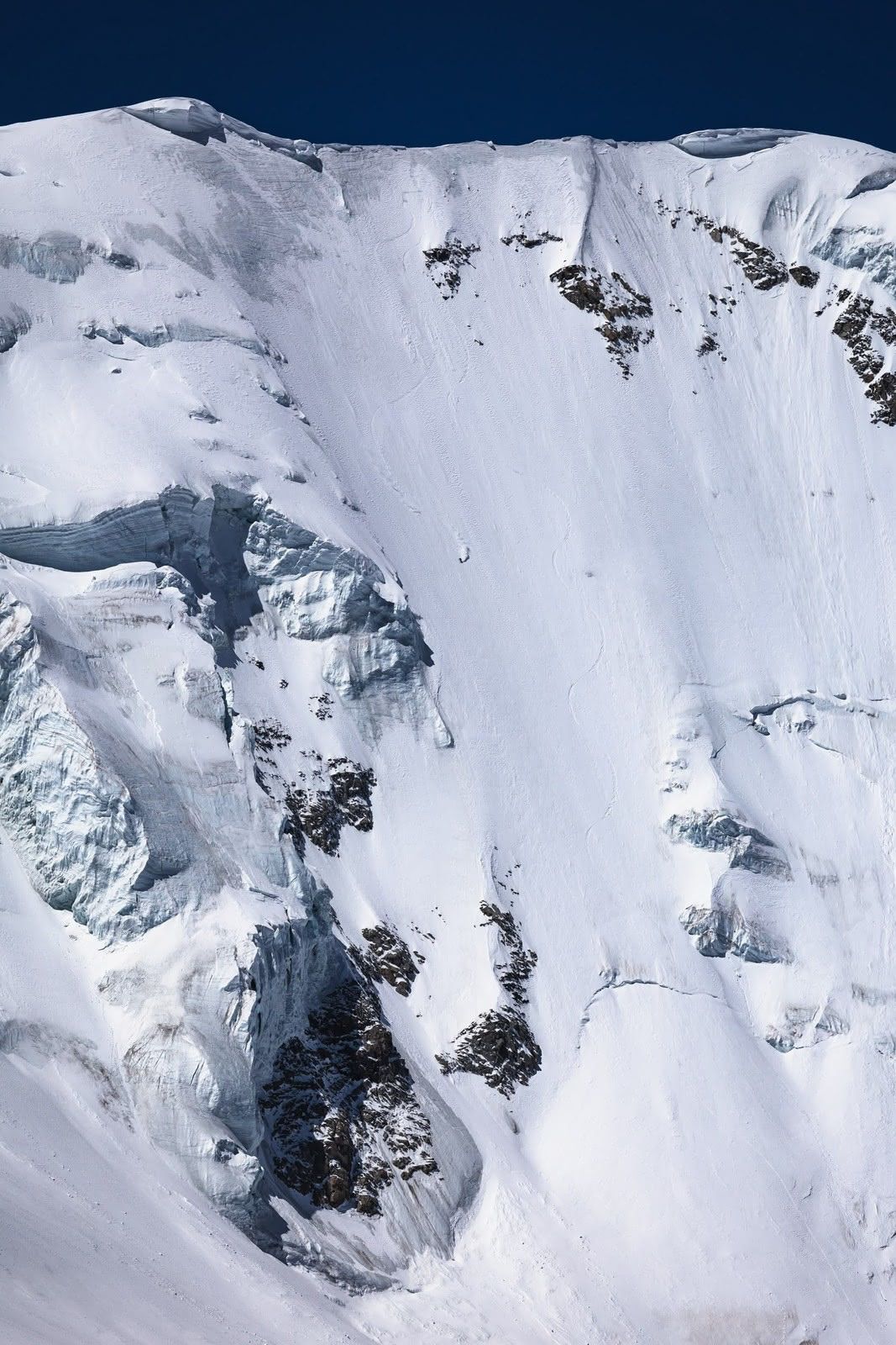 Skiing a glaciated face beneath deep blue sky